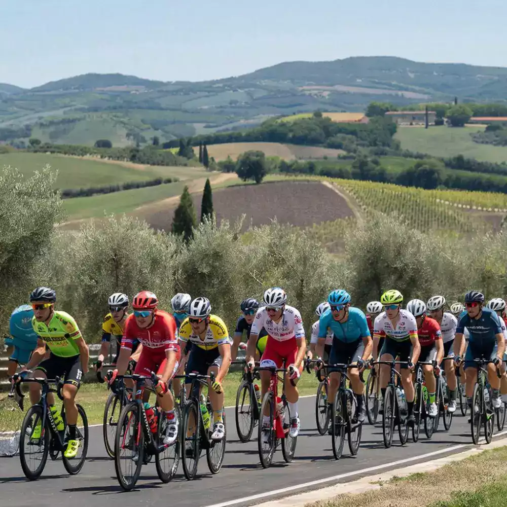 Momento di trionfo e celebrazione quando i ciclisti attraversano entusiasti la linea del traguardo della Gran Fondo Ostia, ricevendo applausi e medaglie per il loro impegno sportivo completato